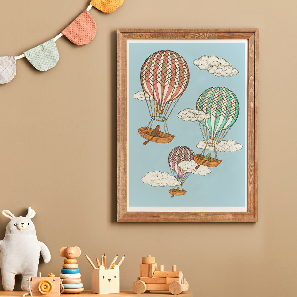 Framed children's illustration of hot air balloons on a beige wall with toys below.