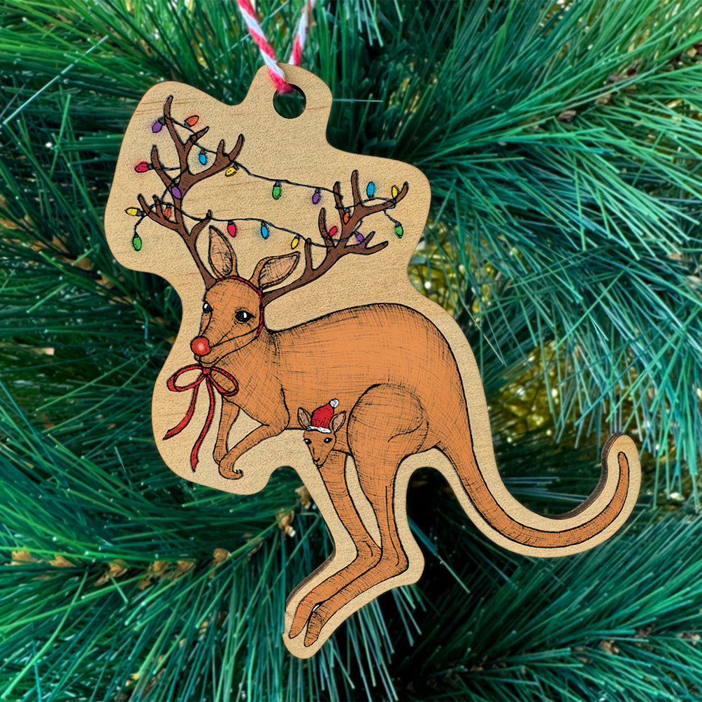 Wooden kangaroo ornament with reindeer antlers on a Christmas tree.