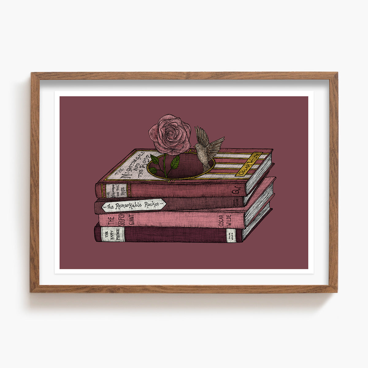 Framed artwork of a stack of Oscar Wilde books with a rose and bird on a maroon background. 