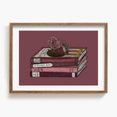 Framed artwork of a stack of Oscar Wilde books with a rose and bird on a maroon background. 