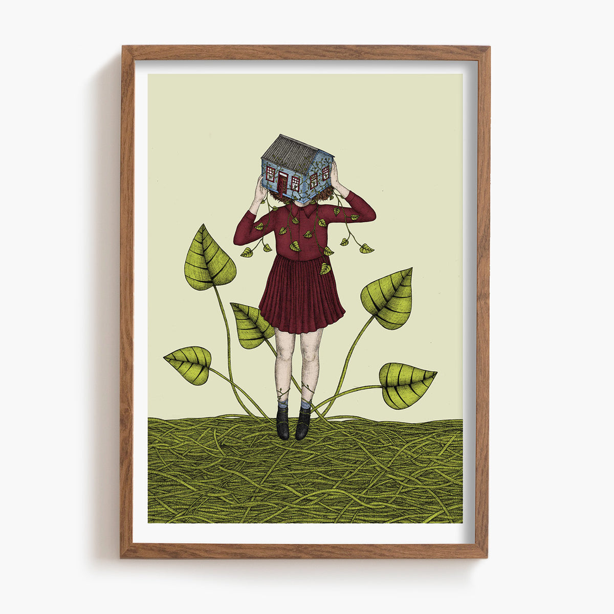 Framed artwork of a person holding a house over their face, standing on vines with leaves.