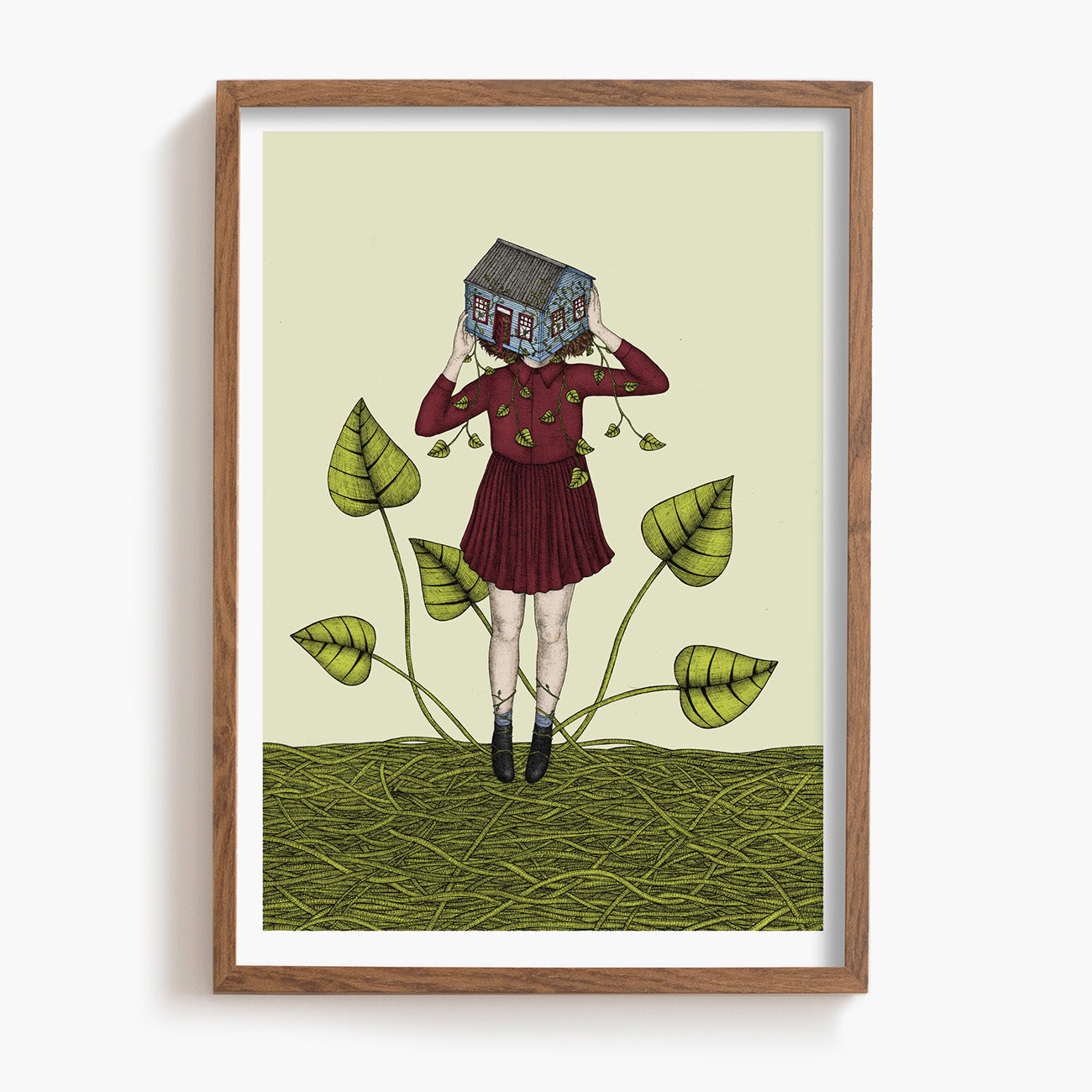 Framed artwork of a person holding a house over their face, standing on vines with leaves.