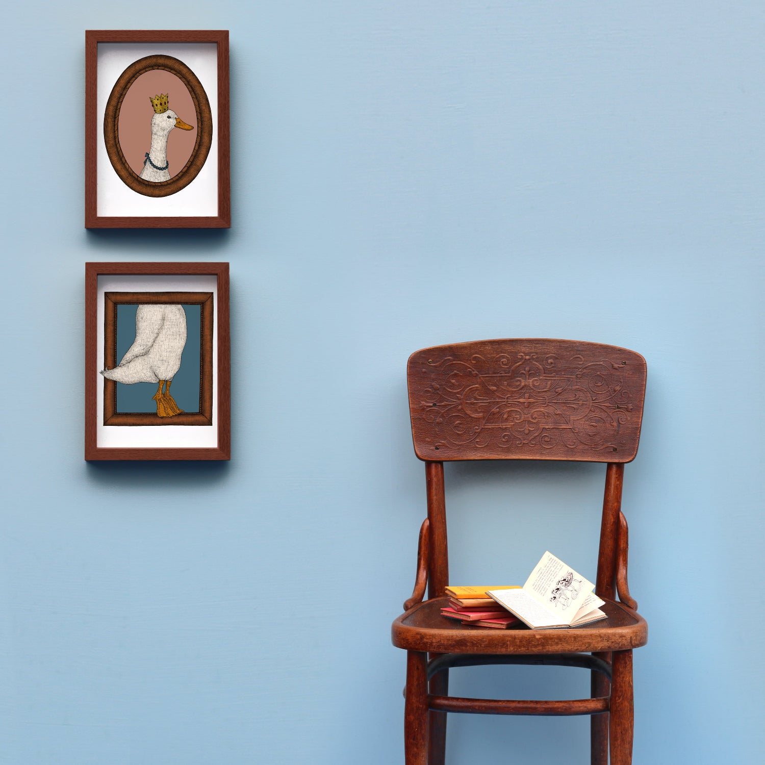 A framed set of duck art prints on a wall with a styled chair