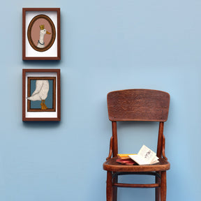 A framed set of duck art prints on a wall with a styled chair