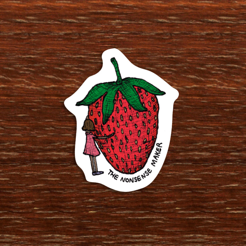 Sticker of a strawberry with a miniature person on a wooden surface