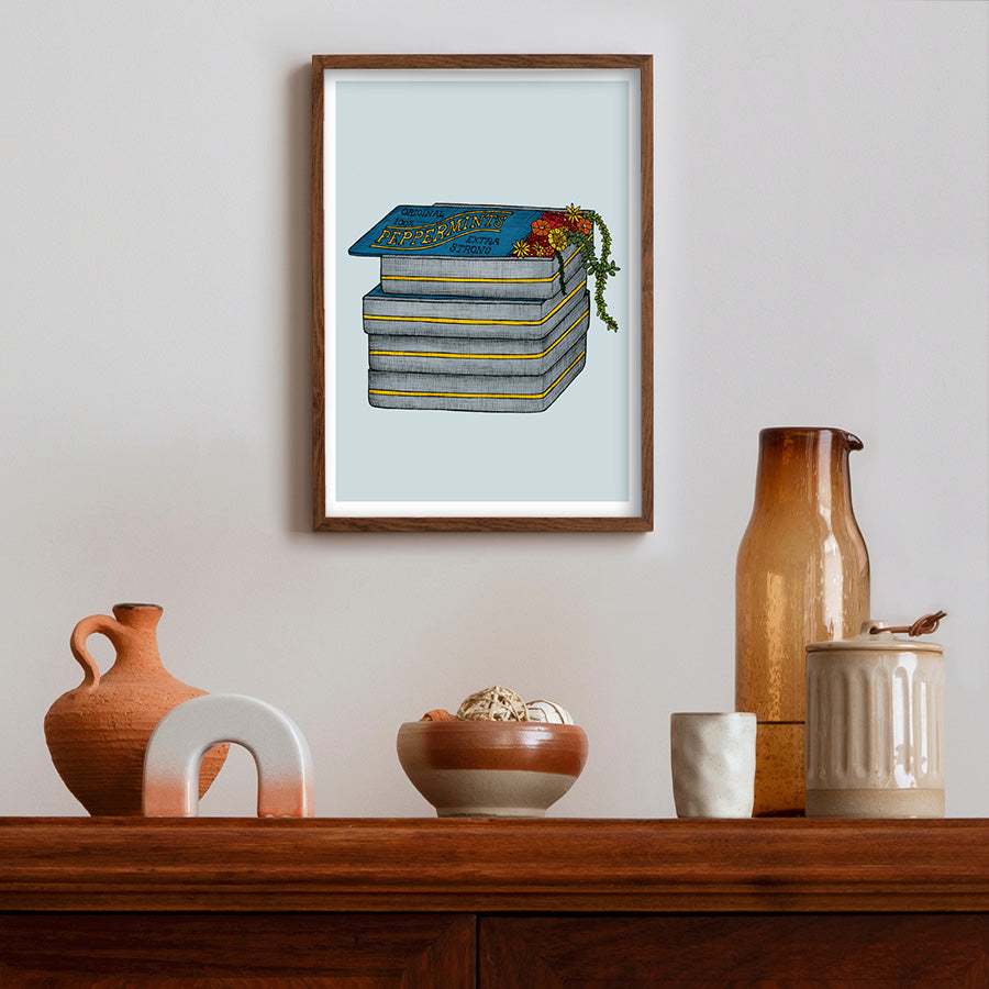 Framed artwork of peppermints on a light blue background above a wooden shelf with decorative items.