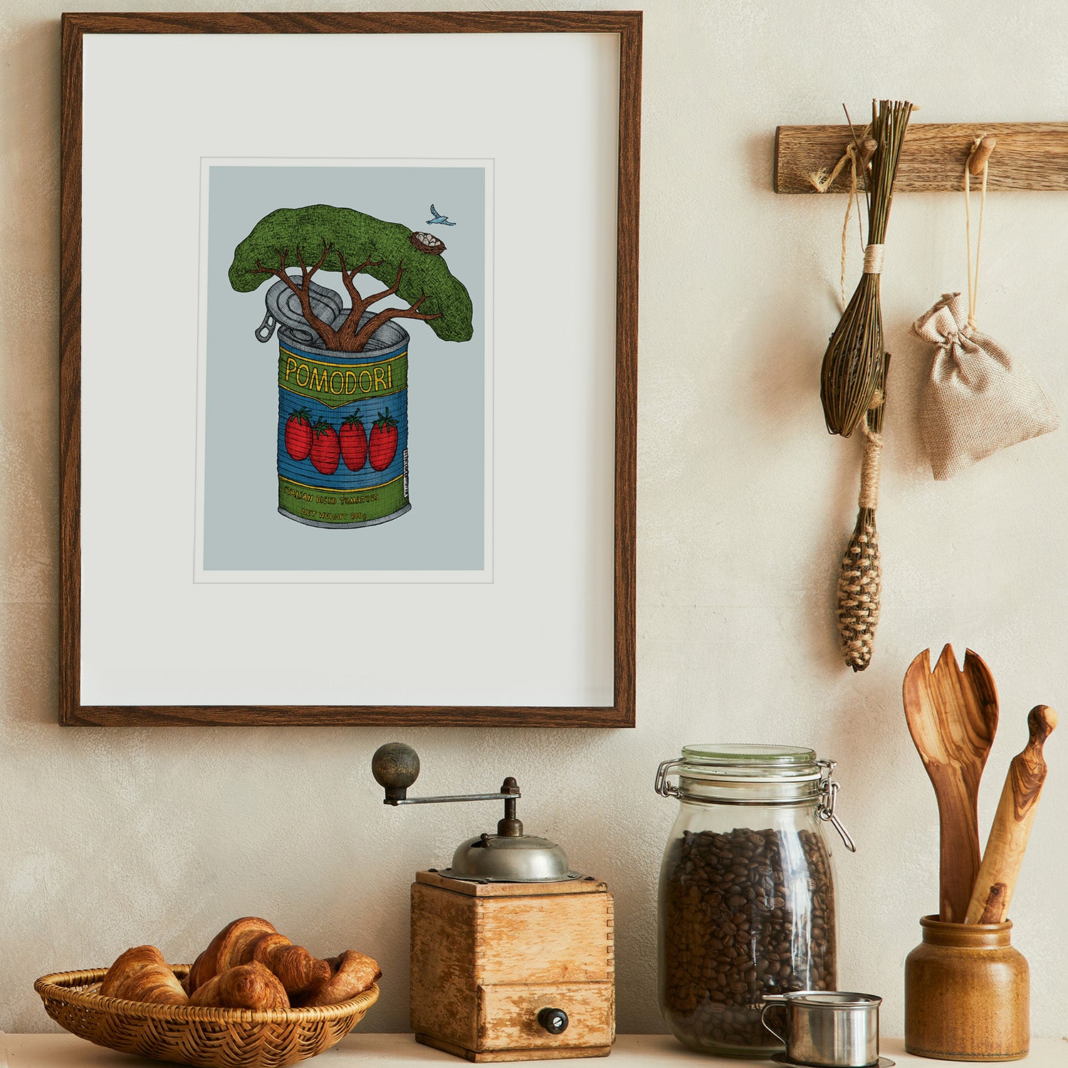 Kitchen wall decor with framed artwork of a tin of tomatoes, coffee grinder, and jars.