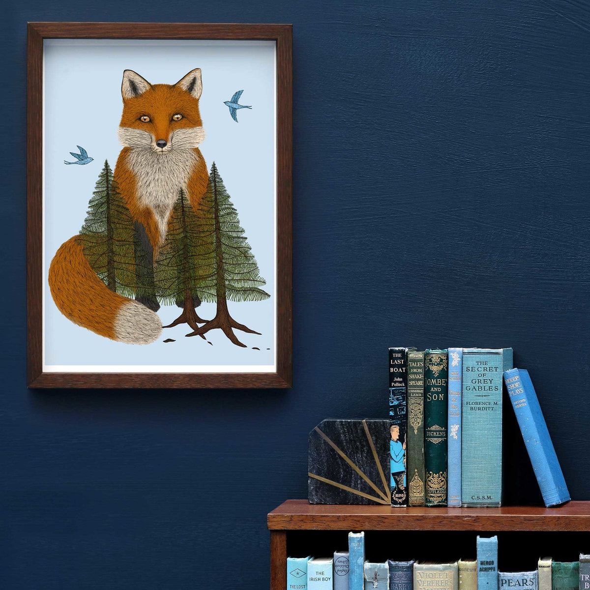 Art print of a fox in the woods on a blue wall next to a bookcase