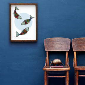 An art print featuring colourful fish swimming amidst purple petals, displayed on a wall above two wooden chairs.
